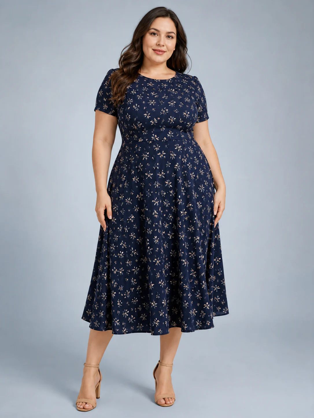 Plus-size model wearing a navy botanical-print midi dress in a blue-gray studio